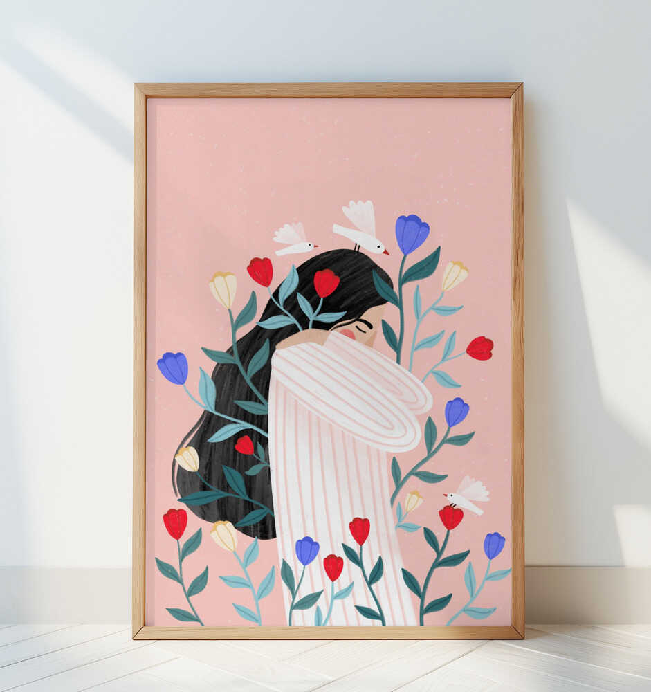 Minimalist poster of a woman embraced by floral elements in red, purple, and cream tones on a blush pink background. The print, framed in oak wood and leaning against a white wall, adds a soft and modern touch to any home interior.