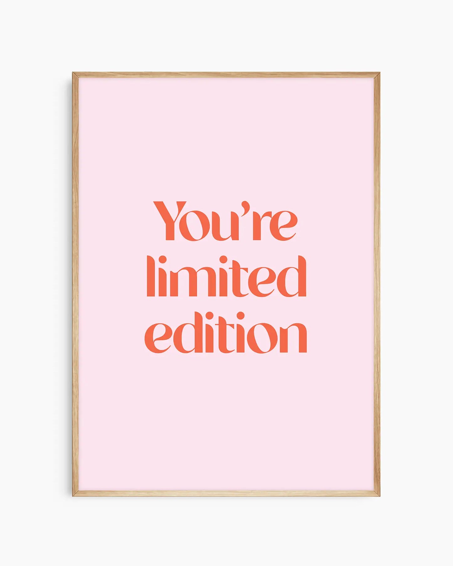 Children's poster with red text 'You're limited edition' on a pink background framed in an oak frame.