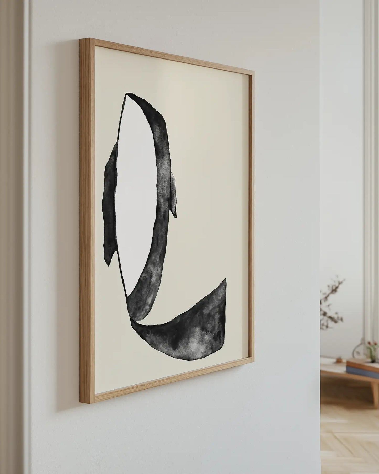 Framed artwork of a killer whale on a wall in a room with a light-colored floor.