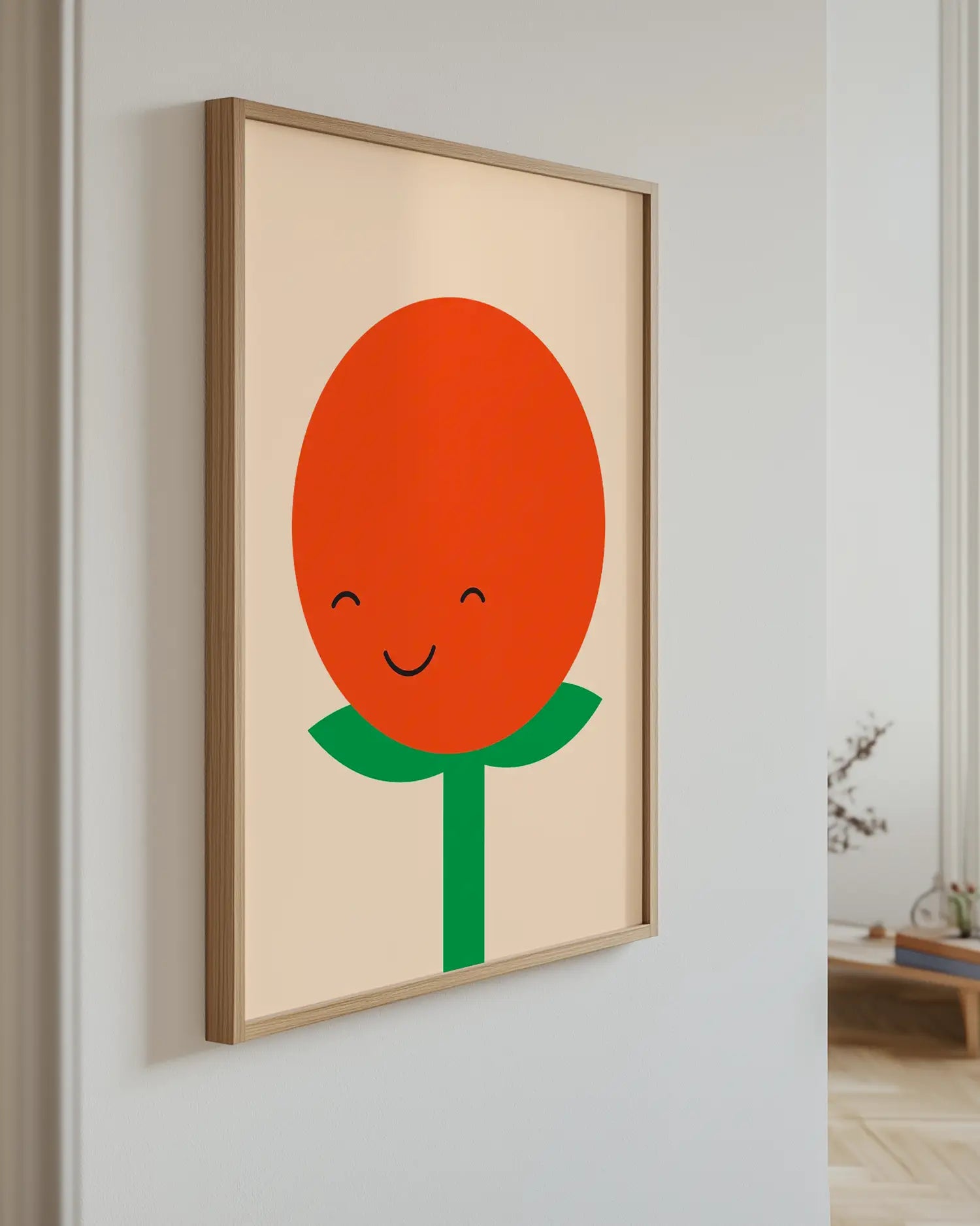 Framed artwork of a smiling tomato with a green stem on a beige background.