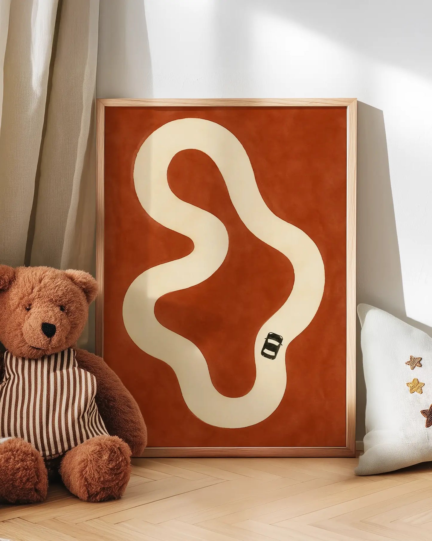 Wallart with a car track on a red background next to a teddy bear and decorative pillow.