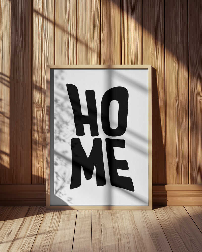Framed nursery poster with the text 'HOME' written in black leaning against the wall. 